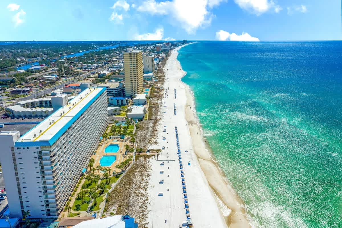 The Summit 927 – Aerial view of a beachside vacation rental with two pools and a long stretch of white sandy beach.