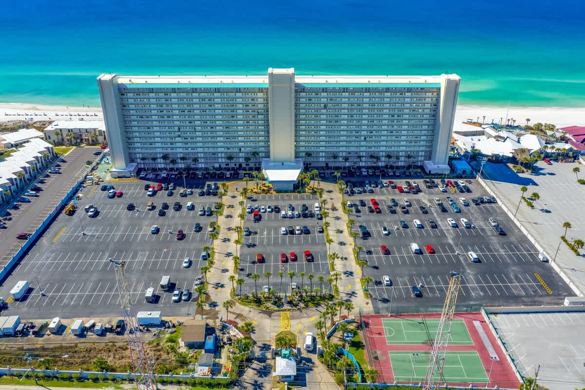 The Summit 927 – Aerial view of The Summit 927, featuring a large building, parking lot, and nearby tennis courts.