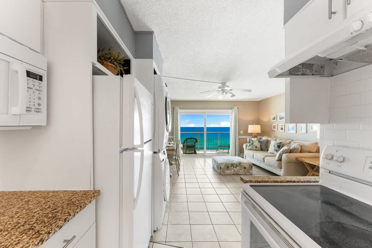 The Summit 927 – Bright kitchen and living area with ocean view, tiled floor, sofa, and dining table.