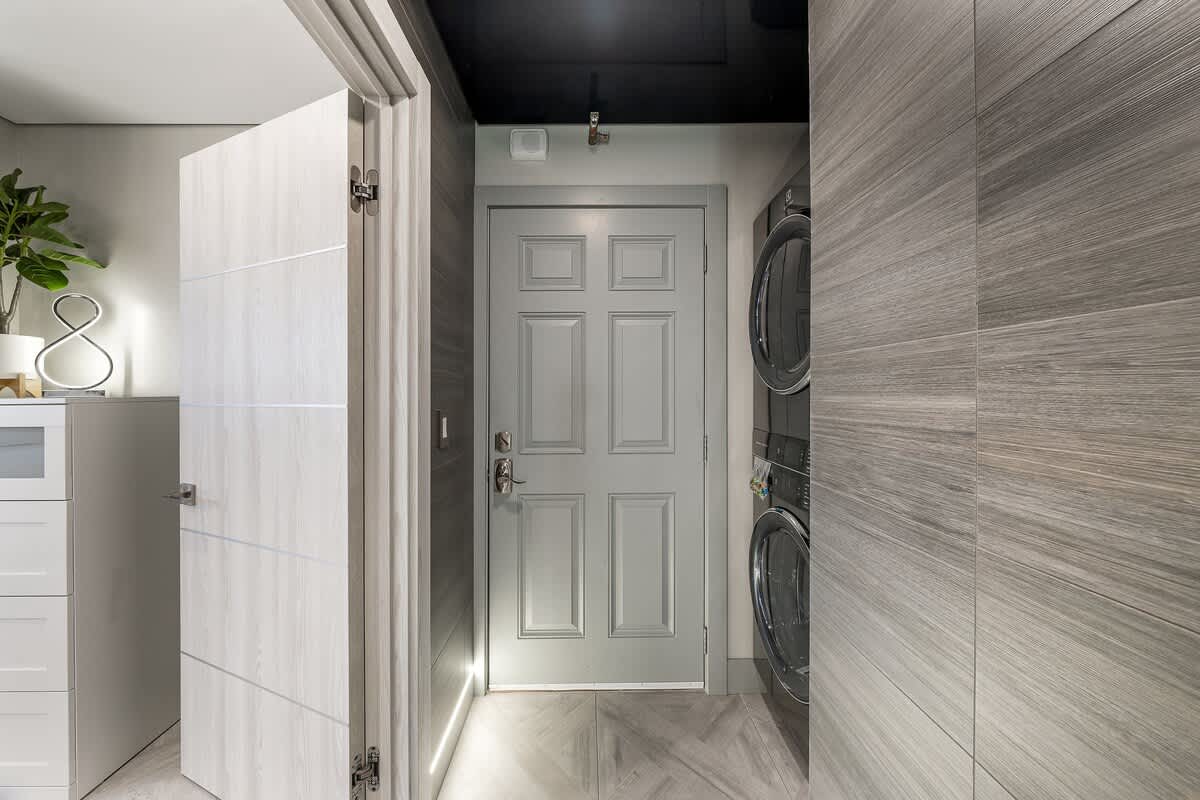 The Summit 1001 – Entrance hallway with a gray door, washer and dryer, and sleek gray wood paneling.
