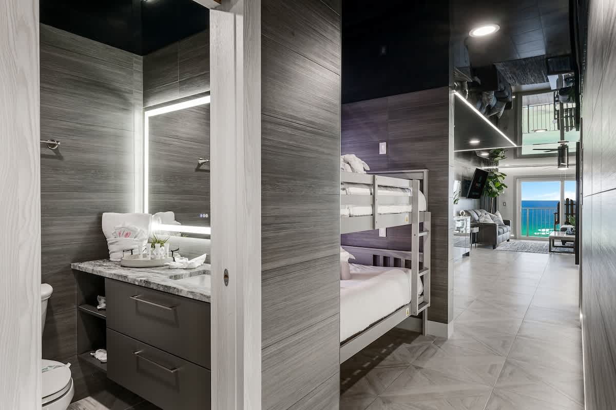 The Summit 1001 – Interior view of a vacation rental featuring a bathroom, bunk beds, and ocean view through large windows.