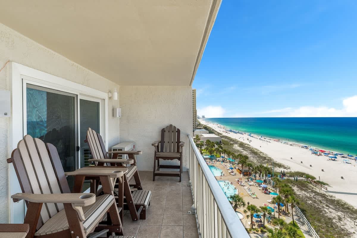 The Summit 1001 – Balcony with wooden chairs overlooking the beach and swimming pool area.