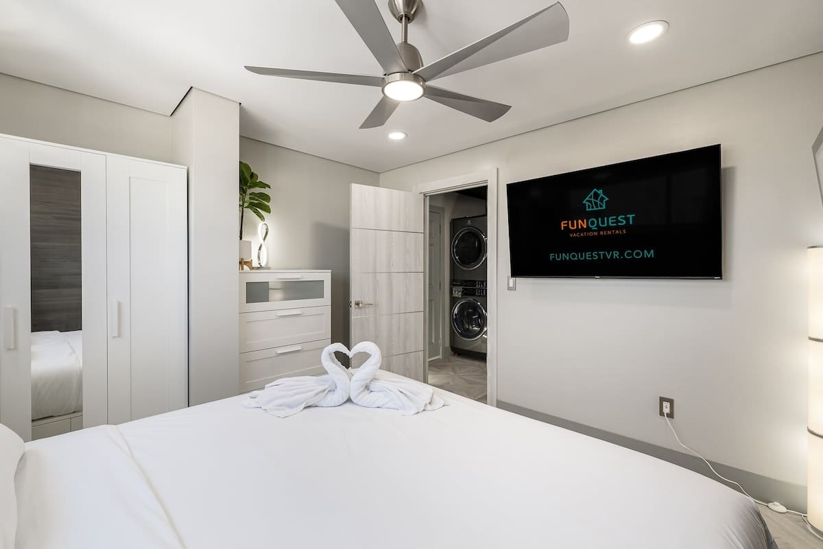 The Summit 1001 – Bedroom with a large bed, ceiling fan, TV, closet, and access to laundry area.