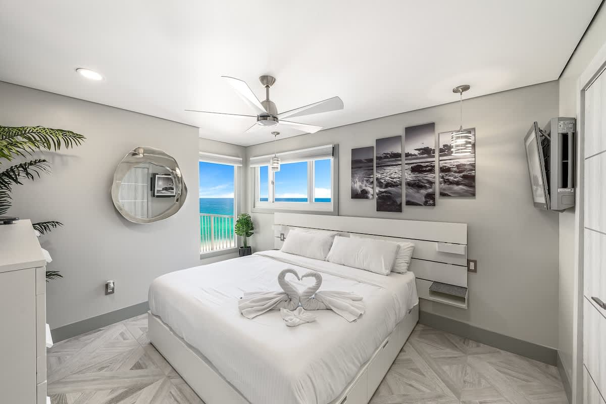 The Summit 1001 – Modern bedroom with a king bed, large windows showing ocean view, and decorative wall art.