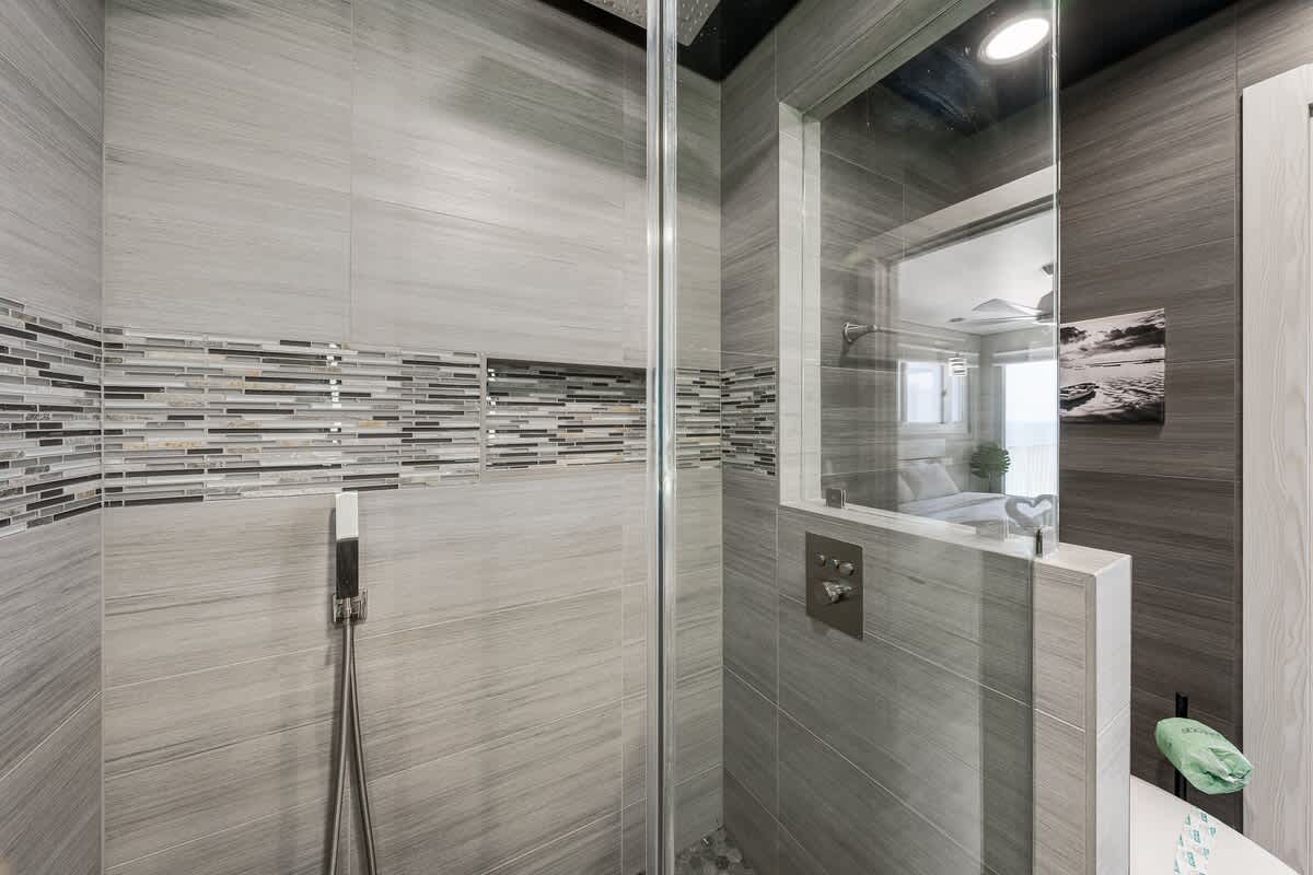 The Summit 1001 – Contemporary shower with gray tiles, glass walls, and decorative mosaic accents.
