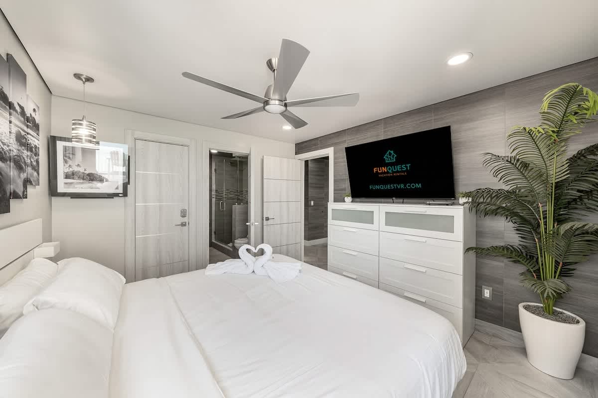 The Summit 1001 – Modern bedroom with a king bed, mounted TV, ceiling fan, and en-suite bathroom access.