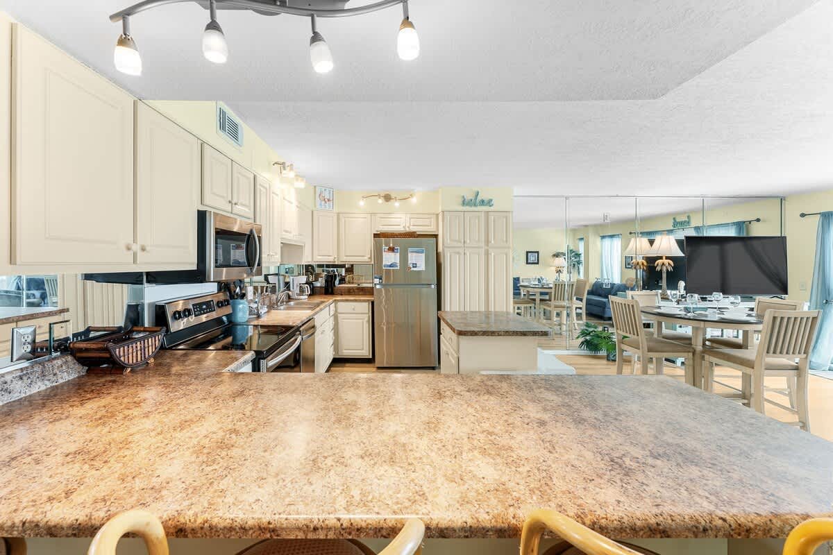 The Summit 1502 – Modern kitchen with granite countertops, stainless steel appliances, and a view into a dining area.