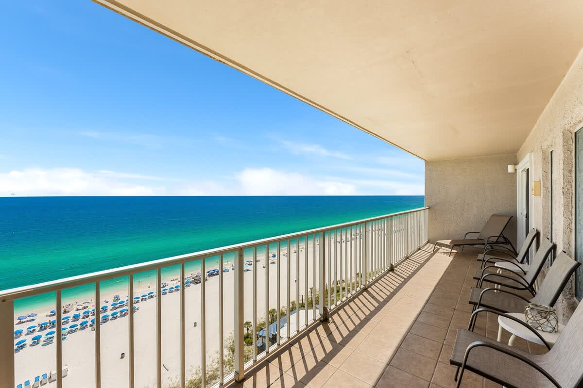 The Summit 1502 – Balcony with chairs overlooking a beach and turquoise ocean view.