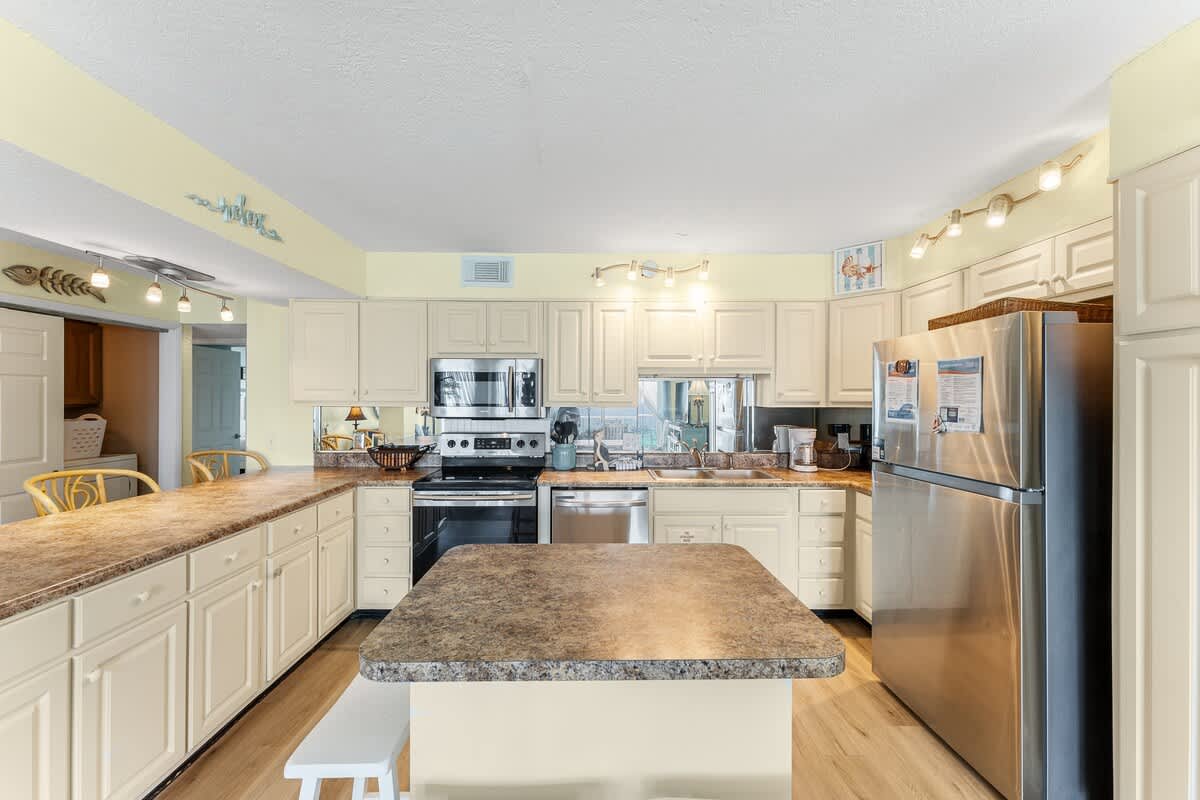 The Summit 1502 – Modern kitchen with stainless steel appliances, granite countertops, and bar seating. Bright, spacious layout.