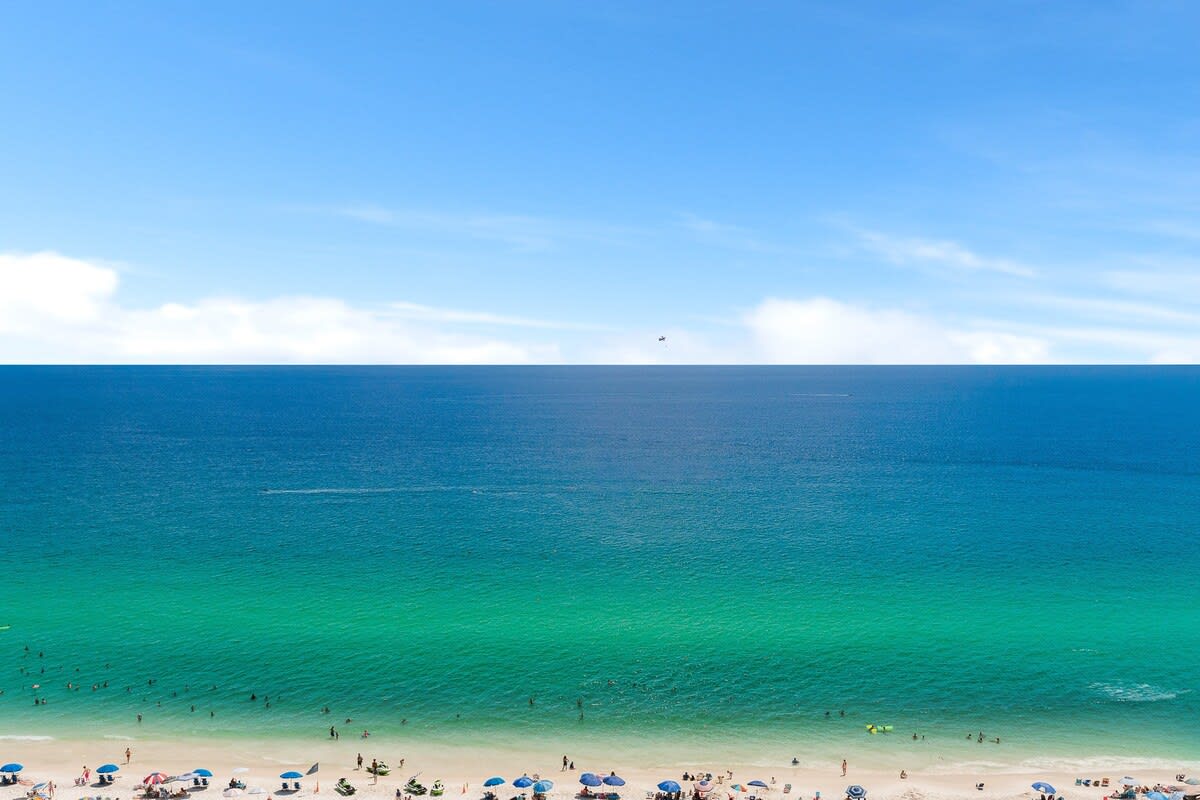 The Summit 1502 – Ocean view from a balcony, with sandy beach and umbrellas visible below.