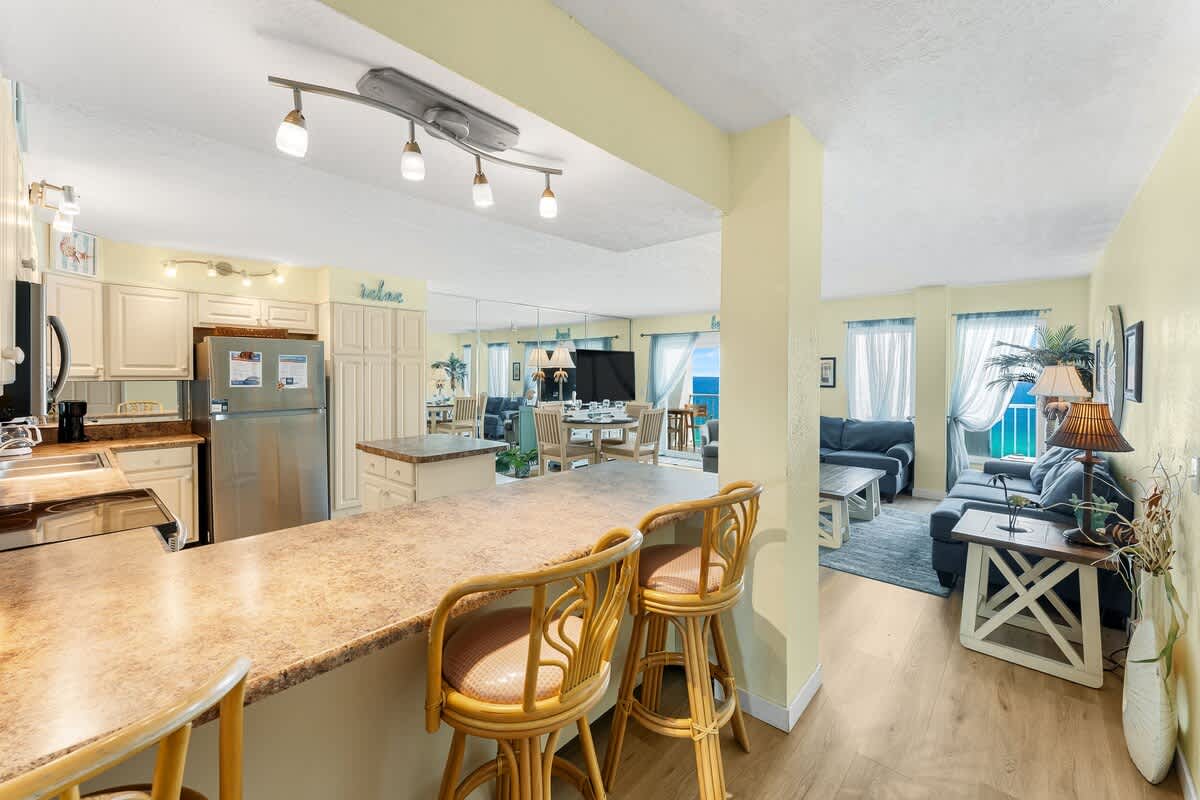 The Summit 1502 – Open-concept living space with kitchen, dining area, and ocean view through large windows.