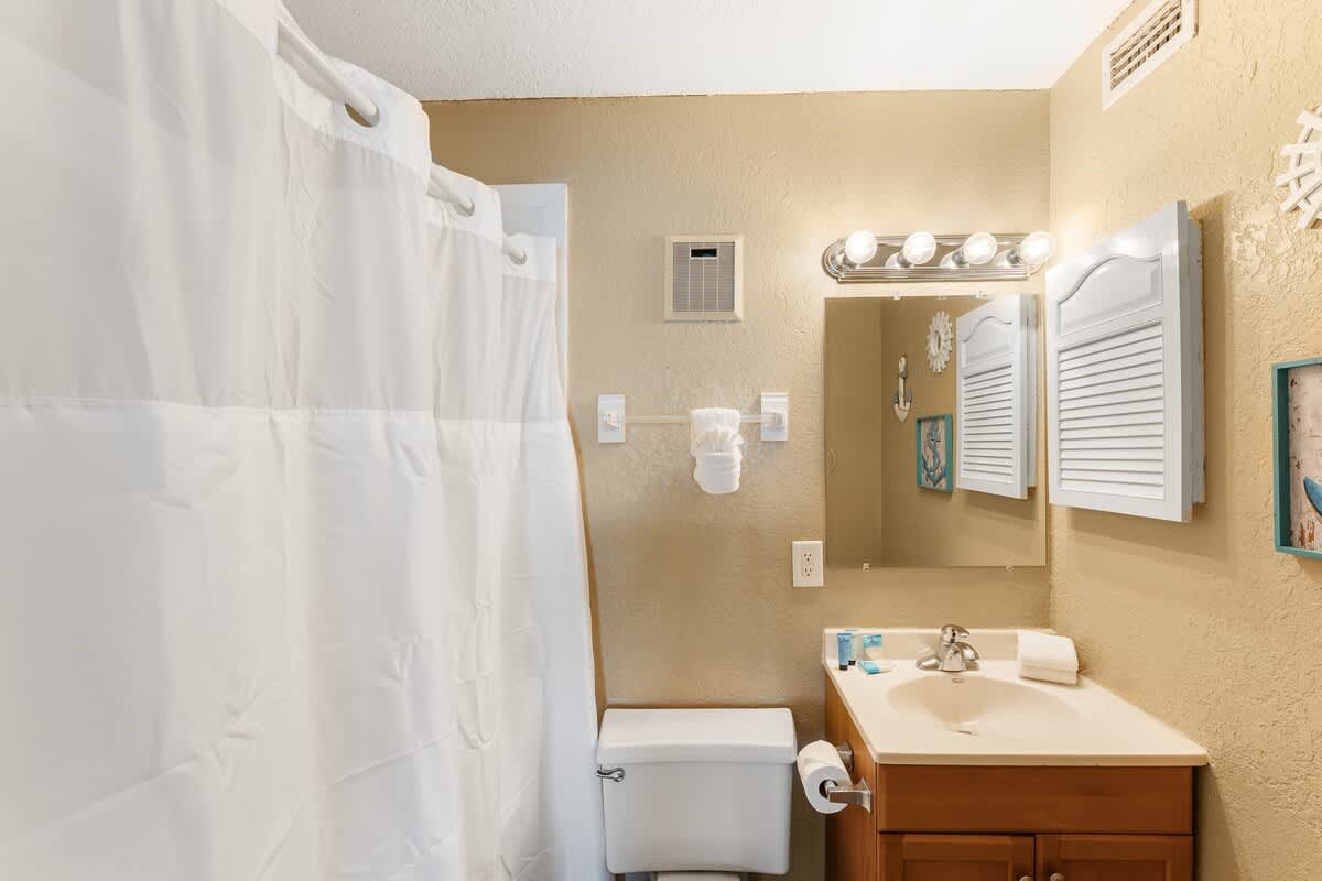 The Summit 1502 – Bathroom with a shower curtain, vanity, mirror, and decorative wall art.