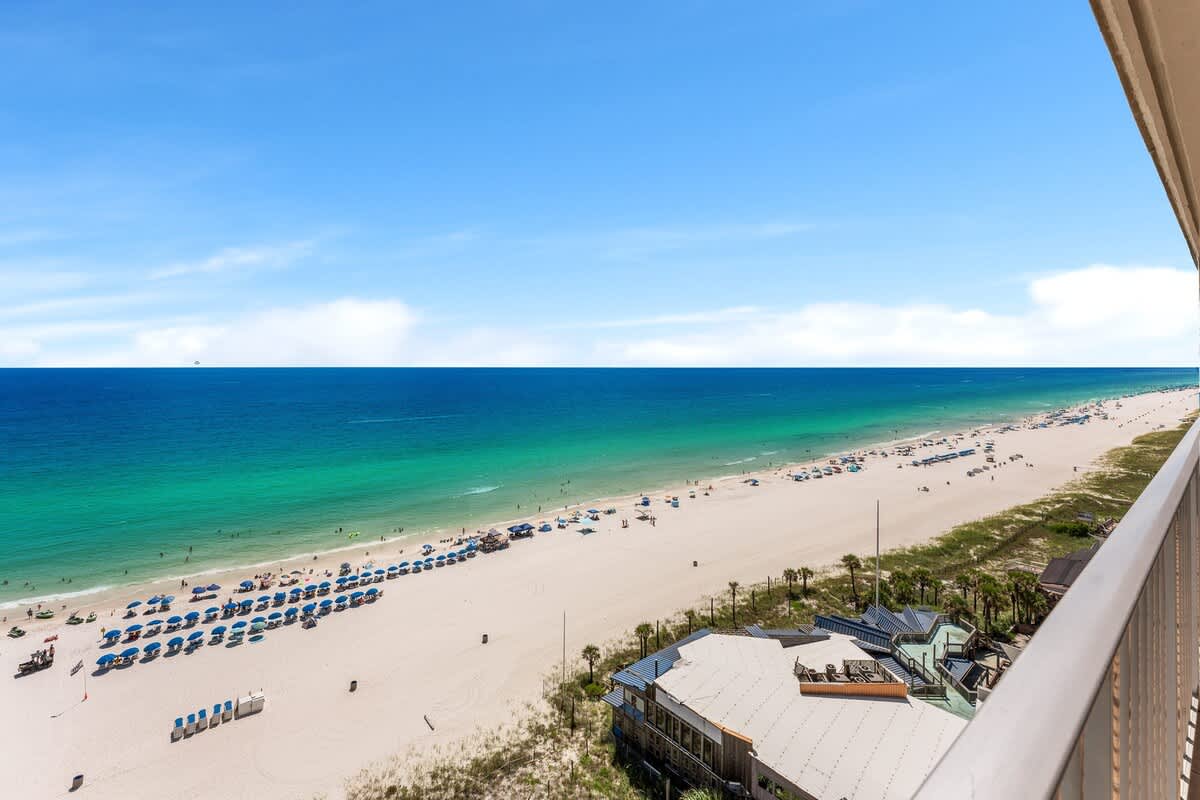 The Summit 1502 – Oceanview from high balcony, featuring sandy beach with umbrellas and clear turquoise water.
