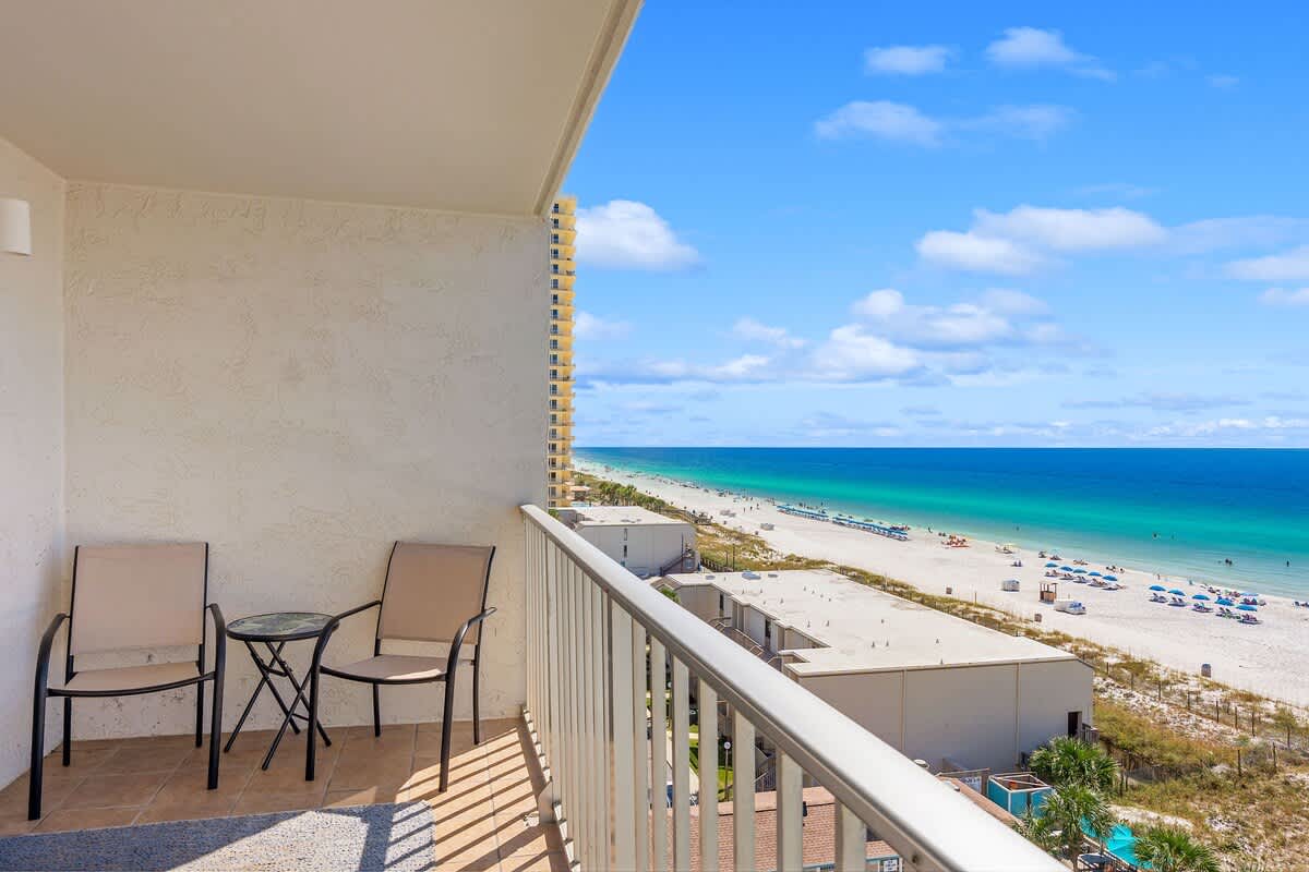 The Summit 828 – Balcony with two chairs and a table overlooking the beach and ocean.