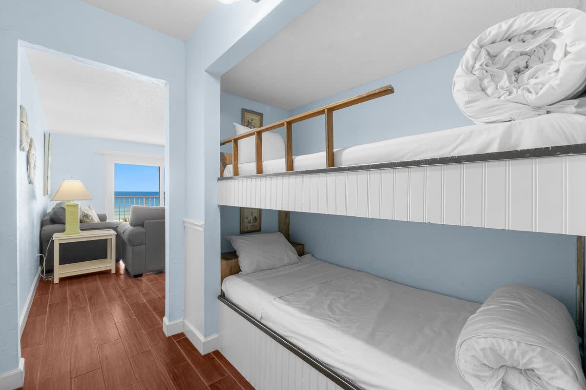 The Summit 408 – Bunk beds in a light blue room with a view of the ocean and a seating area visible.