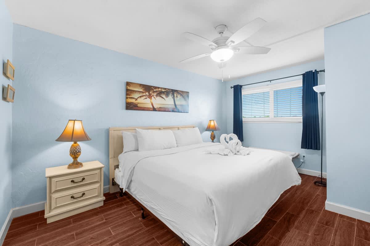 The Summit 408 – Cozy bedroom with a queen bed, blue walls, and natural light from window with blinds.