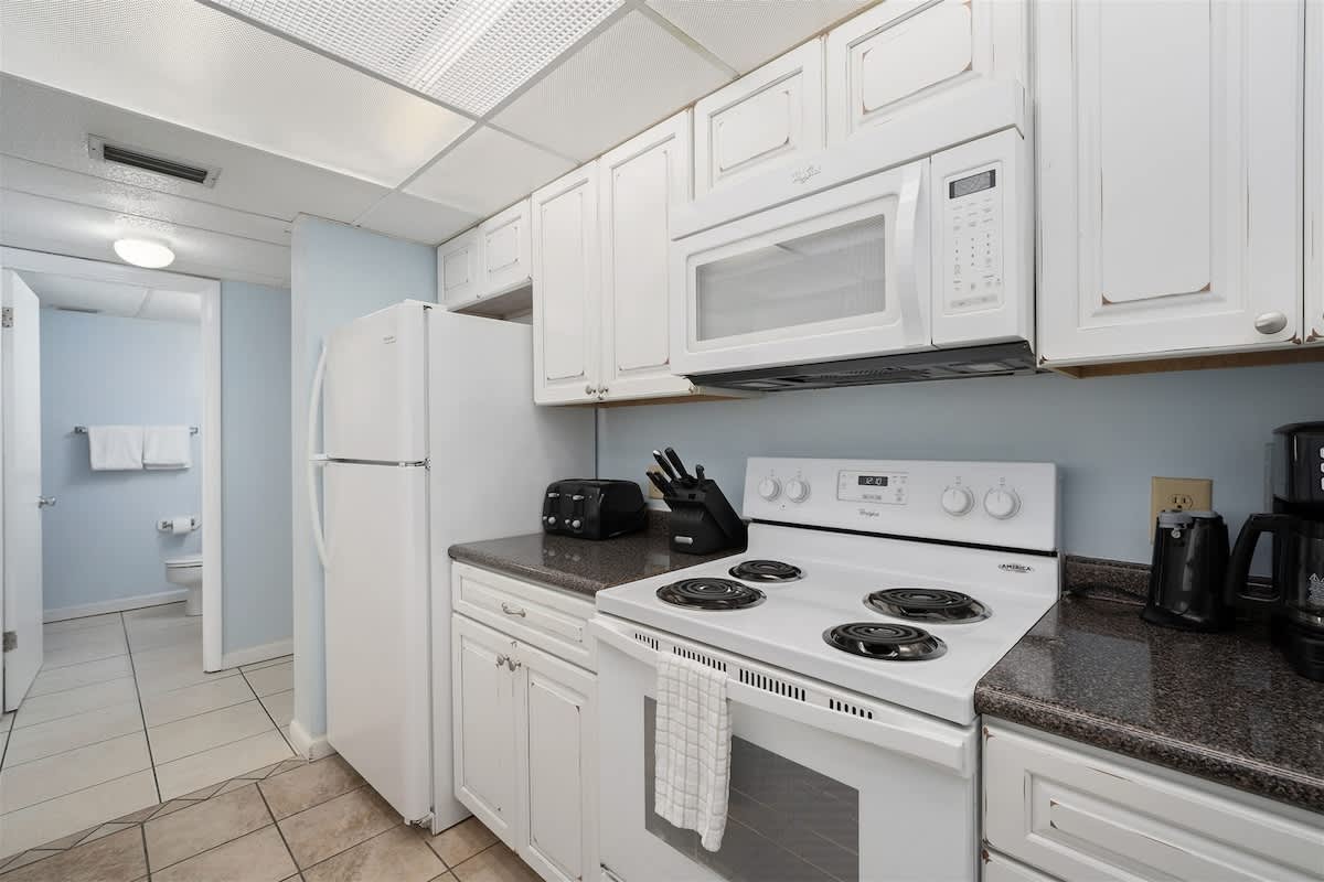 Moondrifter 606 – Kitchen with white cabinetry, appliances, granite countertops, and adjacent bathroom visible in the background.