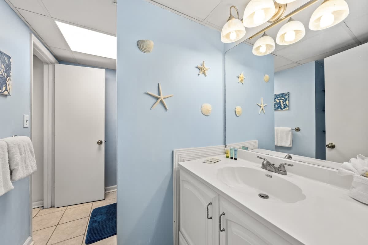 Sunbird 811E – Bathroom with light blue walls, white sink, and decorative seashells on the wall.