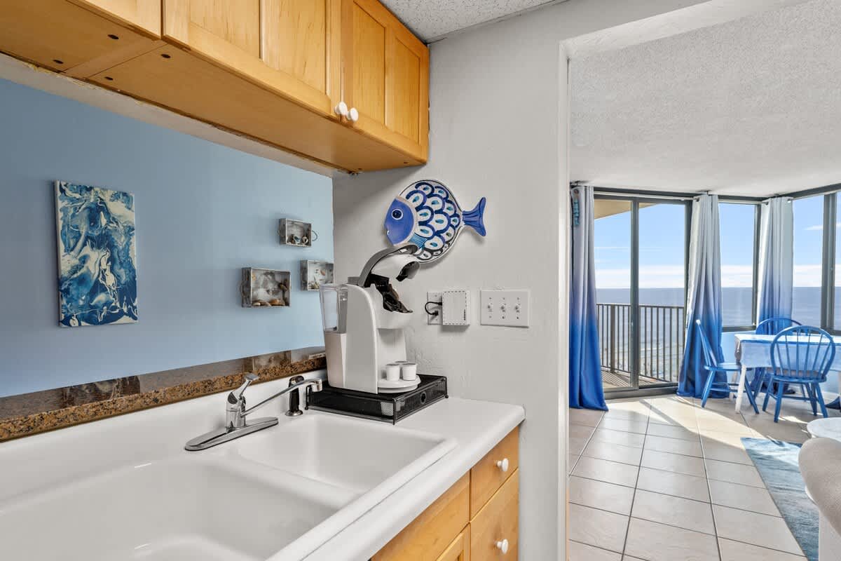 Sunbird 811E – Kitchen area with a sink, coffee machine, and ocean view through large windows.