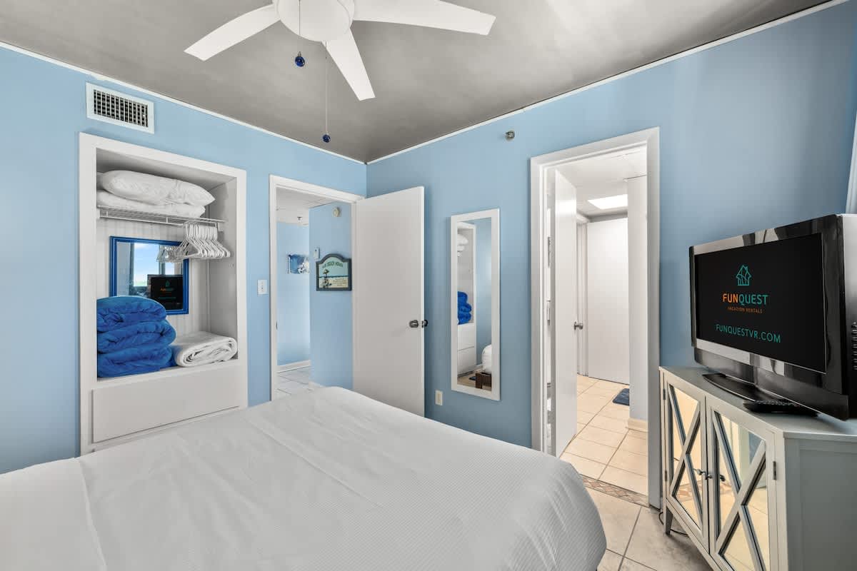 Sunbird 811E – Bright blue bedroom with a ceiling fan, TV, storage closet, and attached bathroom view.