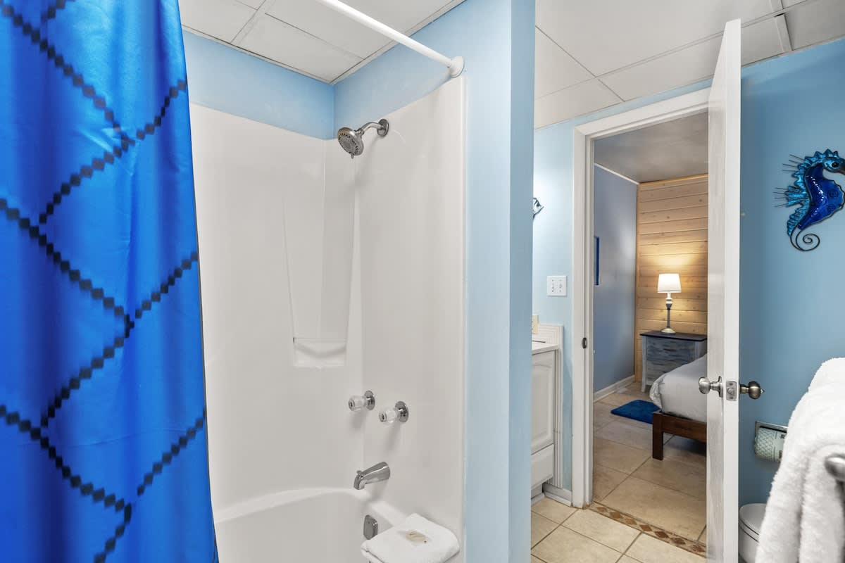 Sunbird 811E – Bathroom with shower, blue walls, white fixtures, view into adjoining room with floor lamp.