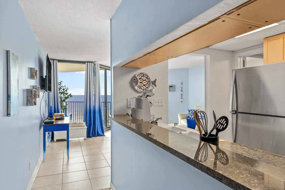 Sunbird 811E – Interior view of a vacation rental with kitchen bar, blue accents, and balcony access with ocean view.