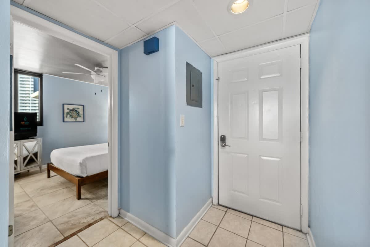 Sunbird 811E – Entryway to a vacation rental featuring a bedroom with a bed and a TV, light blue walls.