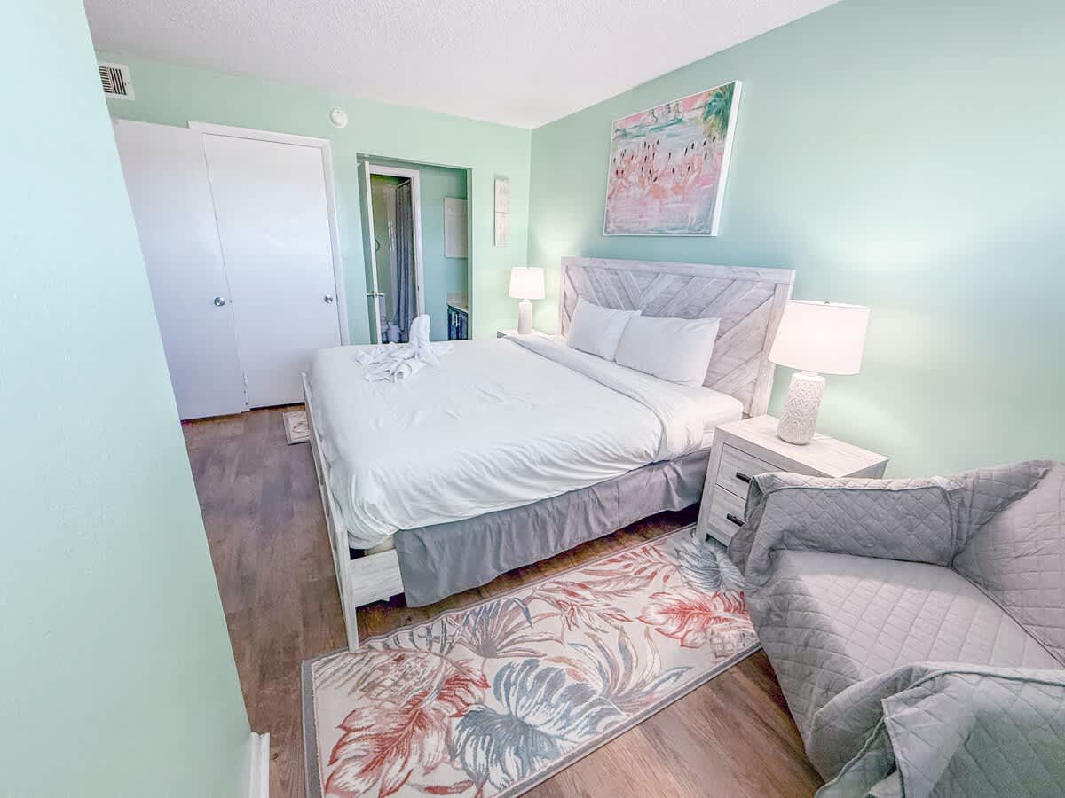 The Summit 524 – Cozy bedroom with a queen bed, bedside tables, armchair, and light green walls.
