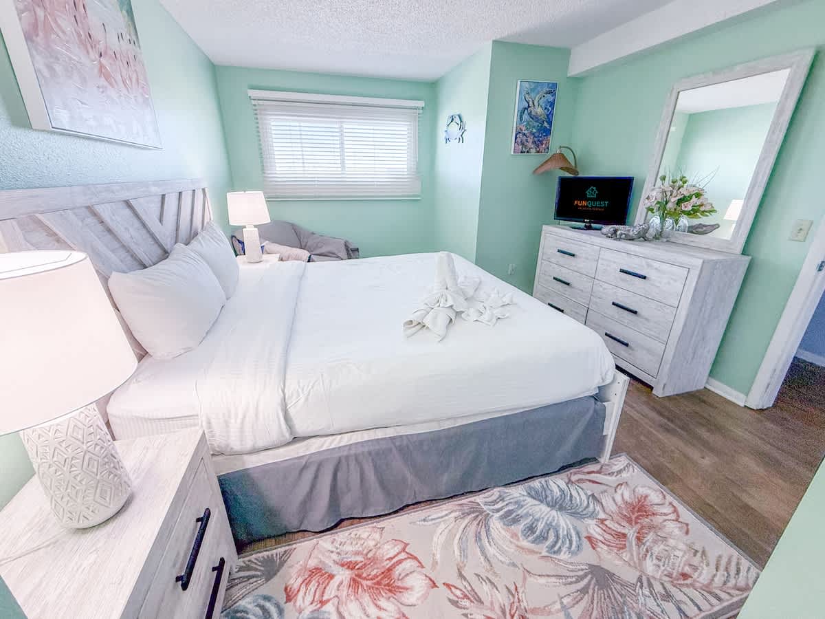 The Summit 524 – Cozy bedroom with a queen bed, dresser, TV, and natural light from a window.
