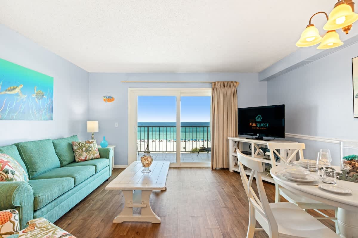 The Summit 524 – Bright living area with teal sofa, dining table, and ocean view balcony.
