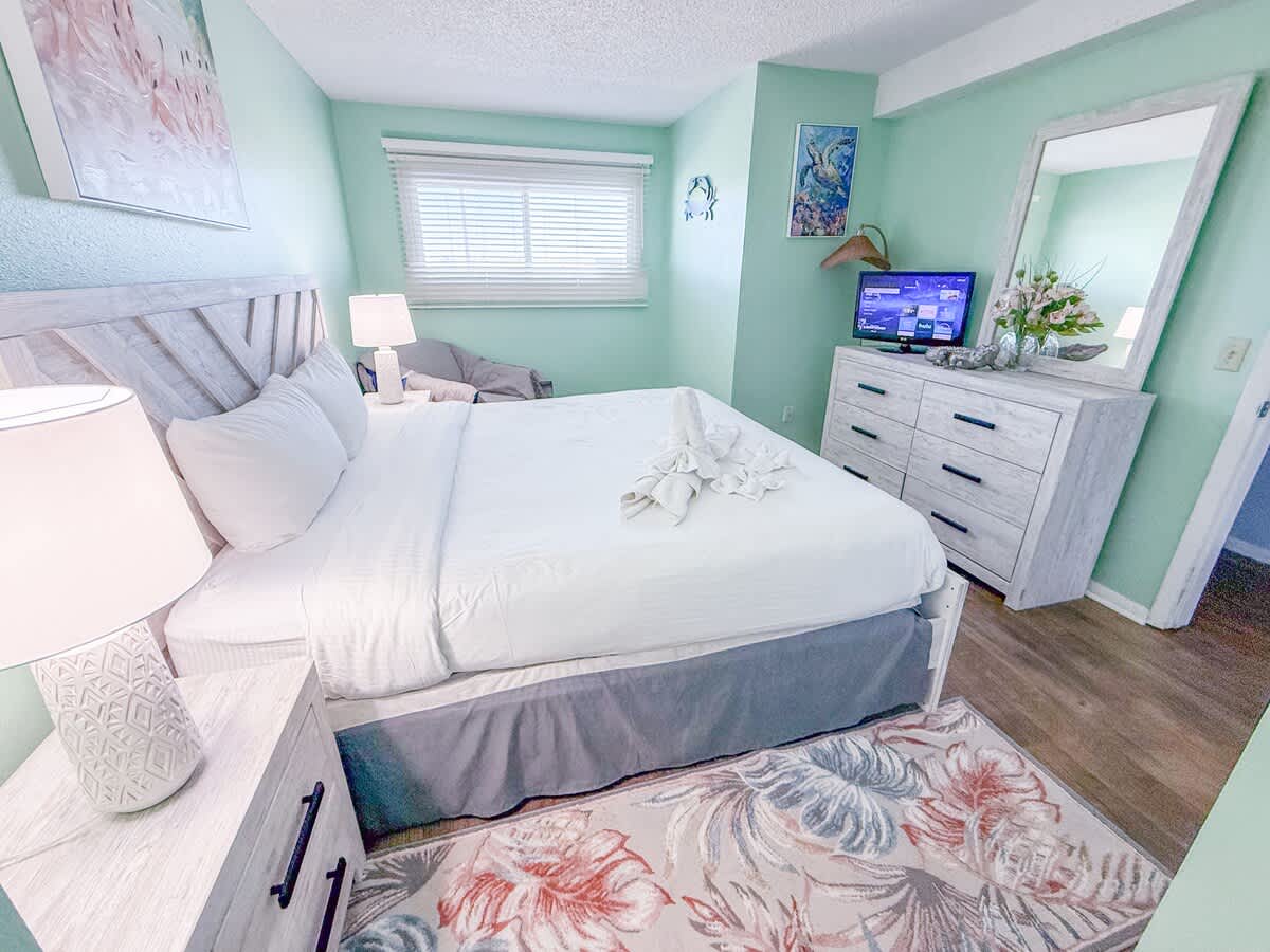 The Summit 524 – Cozy bedroom with a queen bed, dresser, TV, and green walls.
