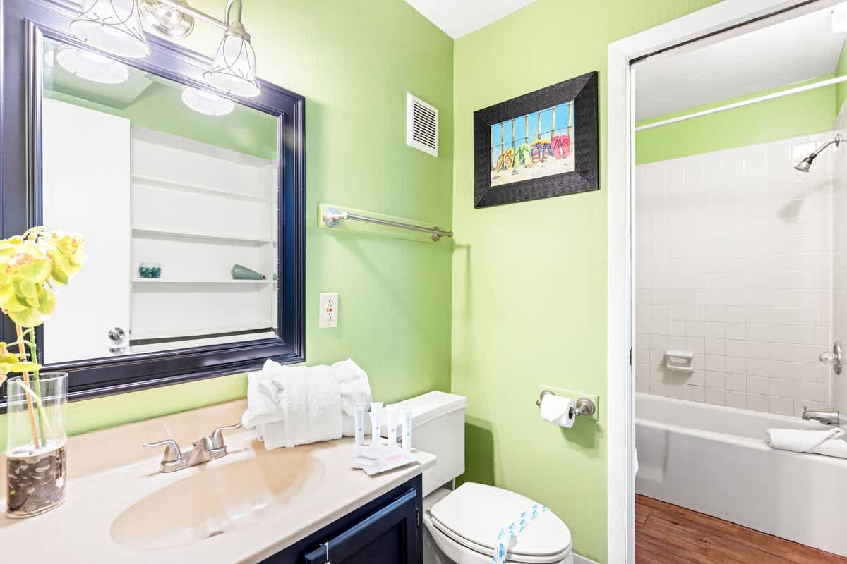 The Summit 524 – Bright green bathroom with a vanity, mirror, artwork, and a shower/tub combo.