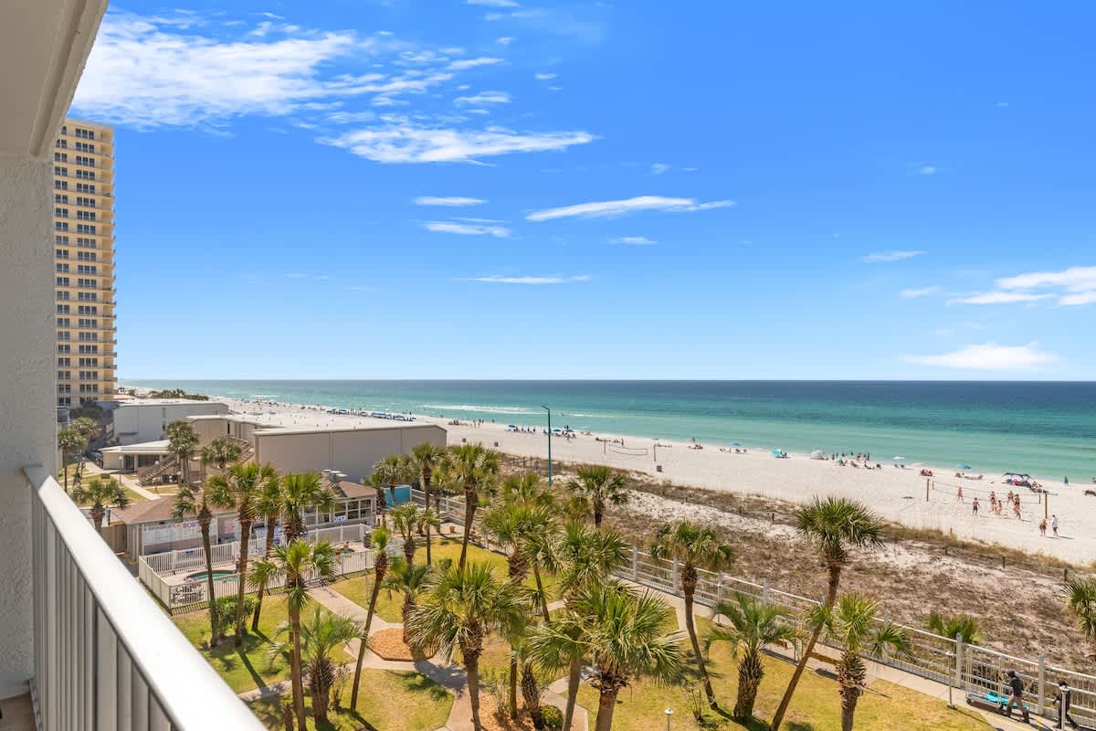 The Summit 524 – Balcony view of beach, palm trees, and ocean with blue skies.