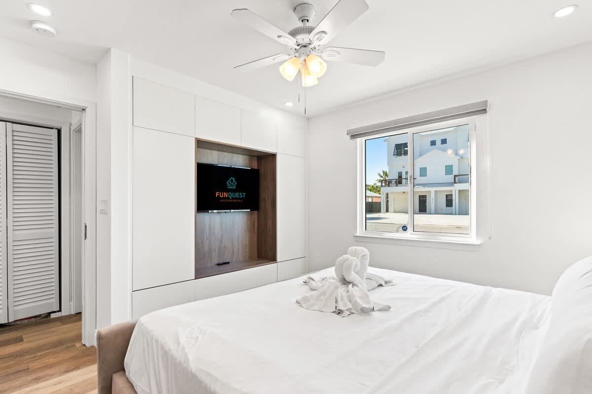 Ocean Breeze 1B – Bright bedroom with a king bed, wall-mounted TV, and window view of the street.
