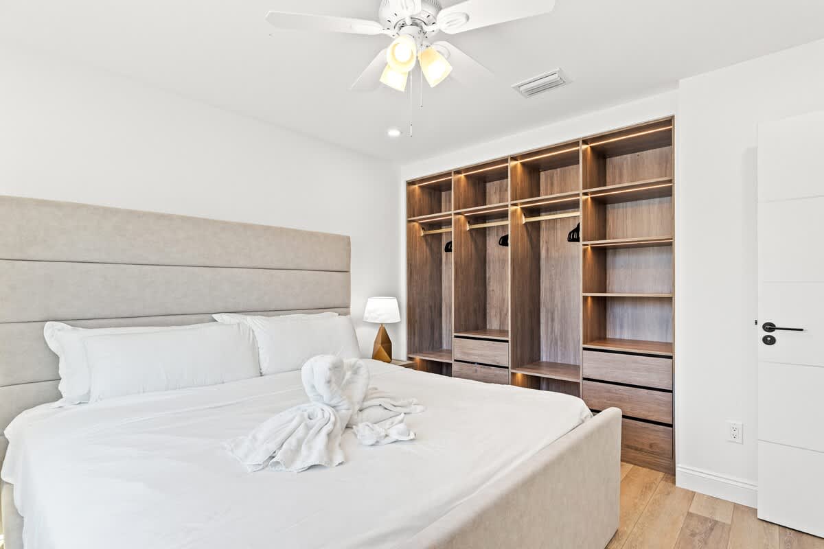 Ocean Breeze 2B – Bedroom with a king-sized bed, ceiling fan, closet space, and light wood flooring.