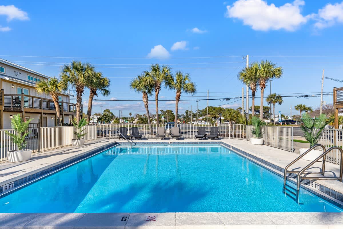 Ocean Breeze 2C – Swimming pool surrounded by palm trees and lounge chairs under a clear blue sky.
