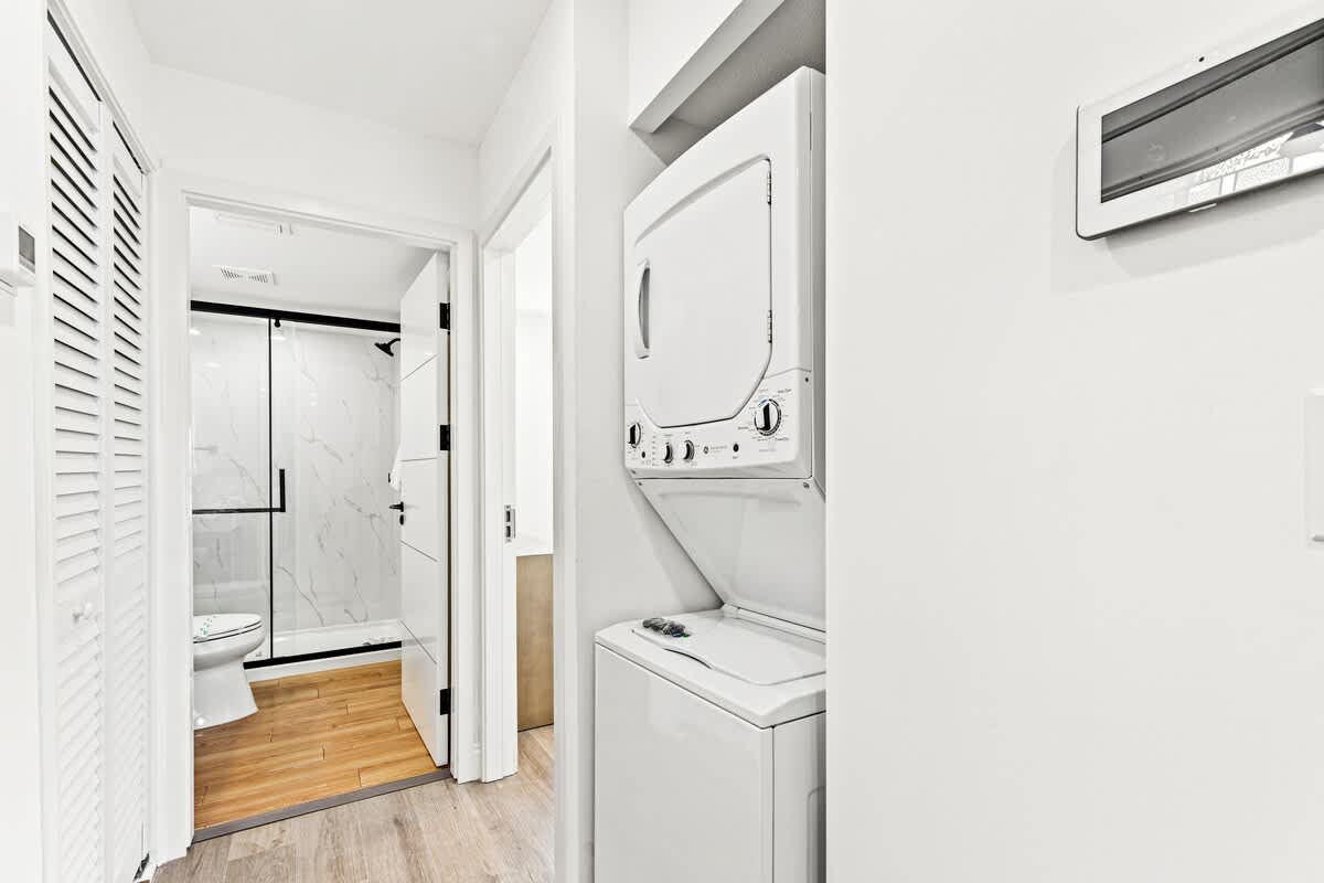 Ocean Breeze 2C – Laundry area with washer and dryer, adjacent to a bathroom with a glass shower.