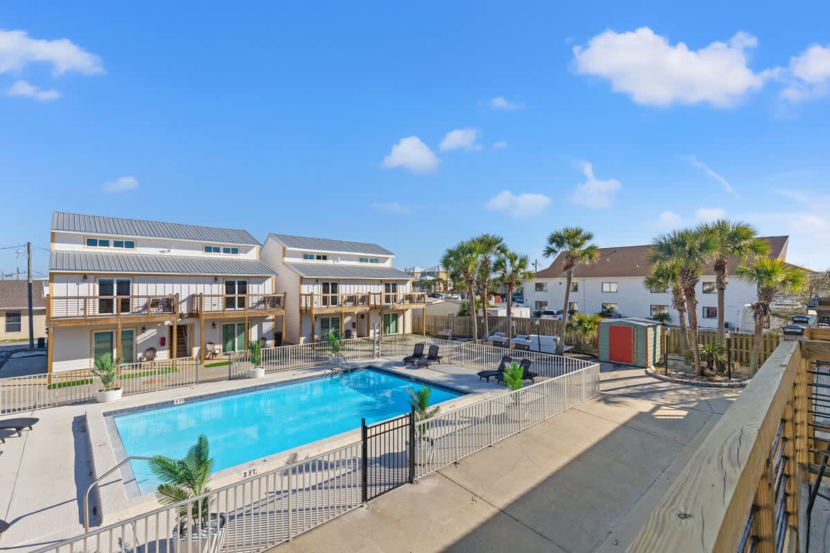 Ocean Breeze 2C – View of a pool surrounded by palm trees and vacation rental buildings.