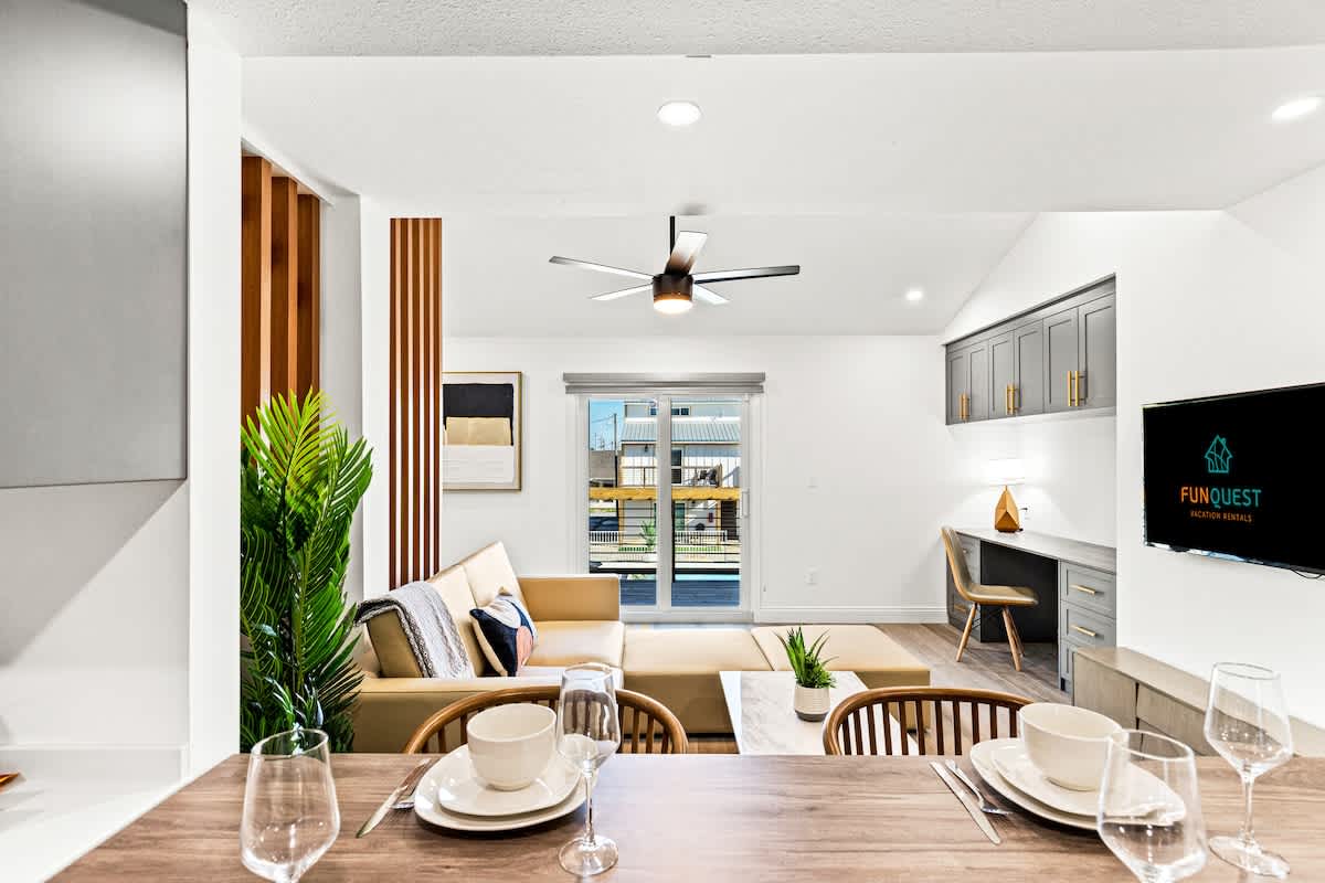Ocean Breeze 2C – Modern living room with a sofa, dining table, and sliding door to a deck.