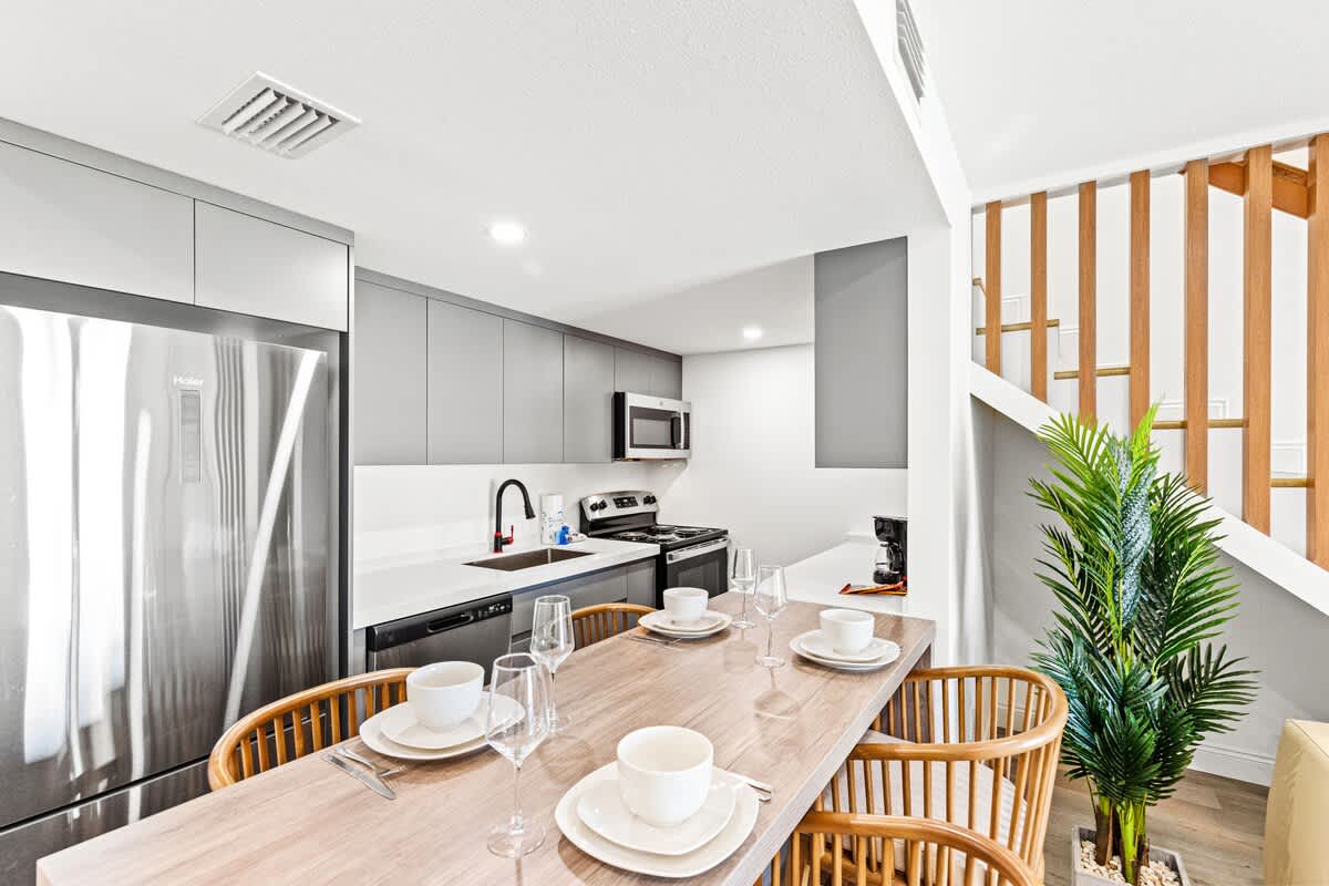 Ocean Breeze 2C – Modern kitchen and dining area with stainless appliances, wooden table, and potted plant.