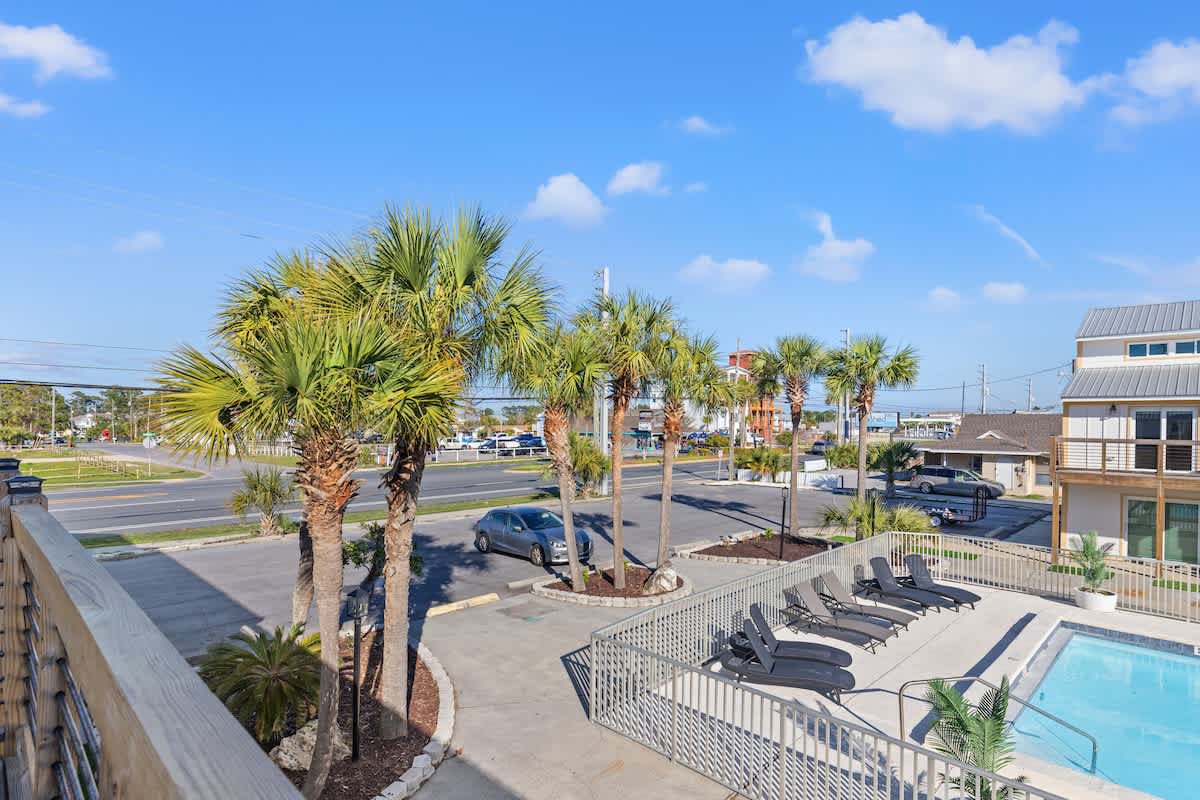 Ocean Breeze 3C – View of palm trees, parking lot, and swimming pool from a balcony.