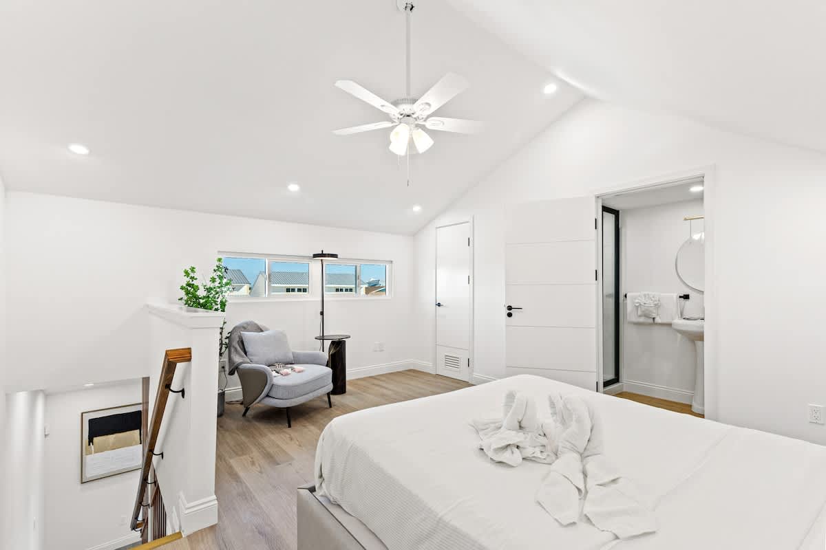 Ocean Breeze 3C – Bright bedroom with a ceiling fan, a seated area, and an en-suite bathroom visible.
