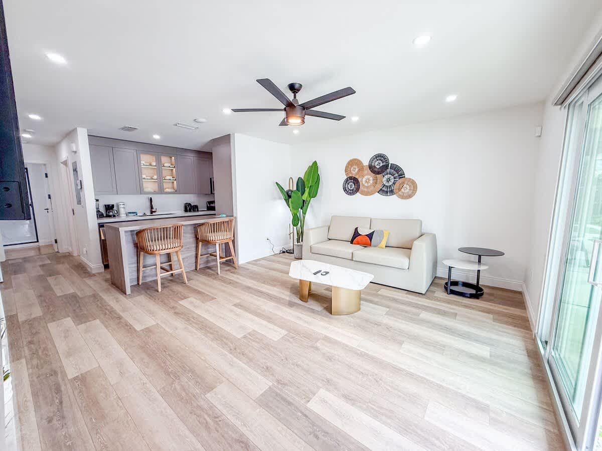 Ocean Breeze 5A – Spacious living area with light-colored furniture, a kitchen bar, and large windows.