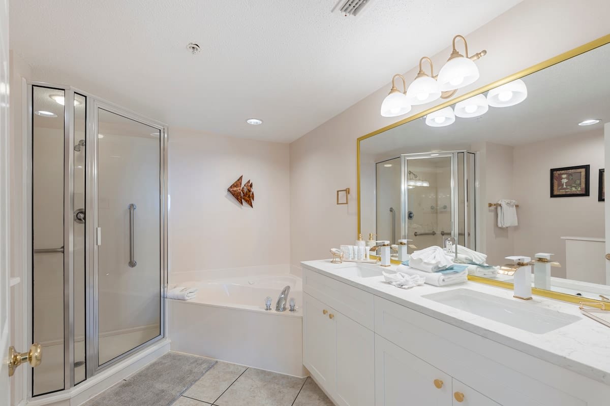 Majestic T2 - 1606 – Spacious bathroom featuring shower, jacuzzi tub, double sinks, and modern lighting.