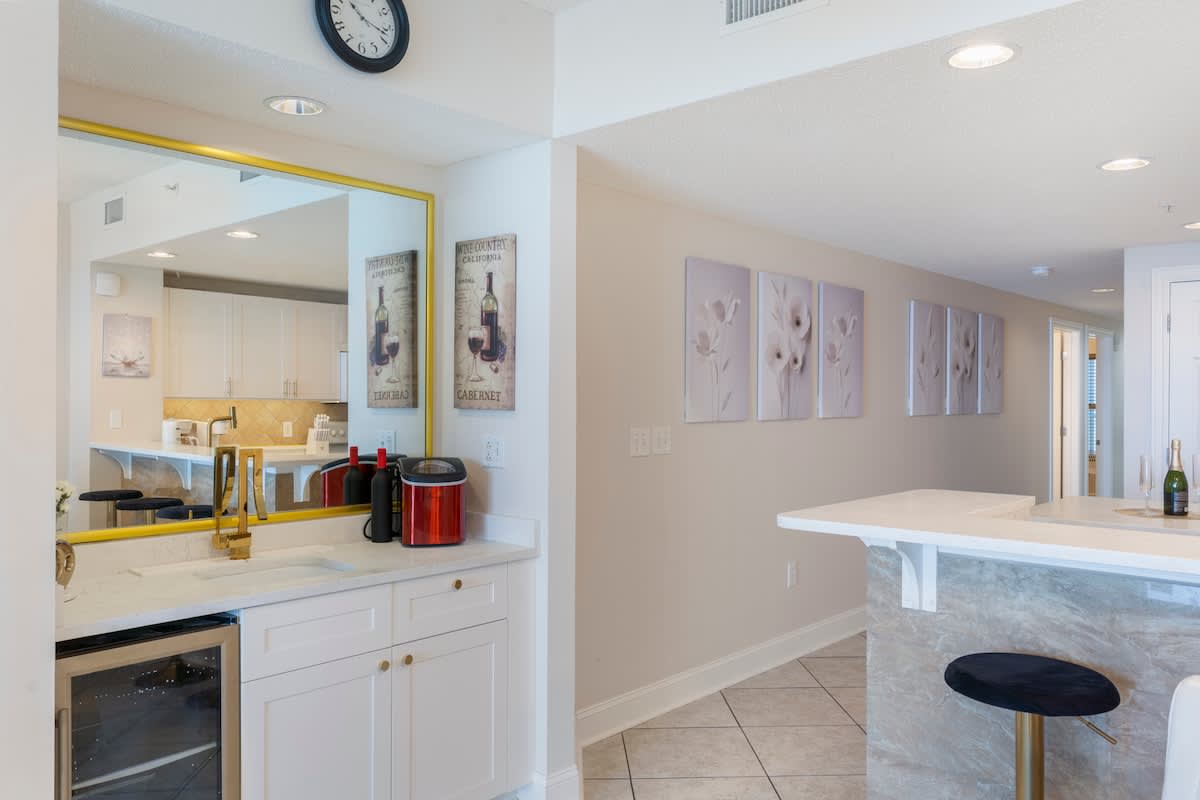 Majestic T2 - 1606 – Kitchen area with white cabinets, marble countertops, bar seating, and decorative wall art.