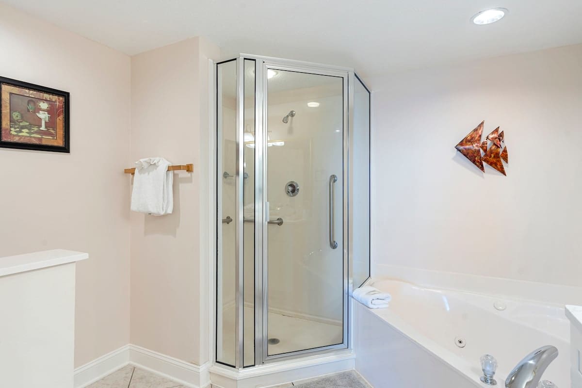 Majestic T2 - 1606 – Bathroom with a glass shower, bathtub, towel rack, and decorative wall art.