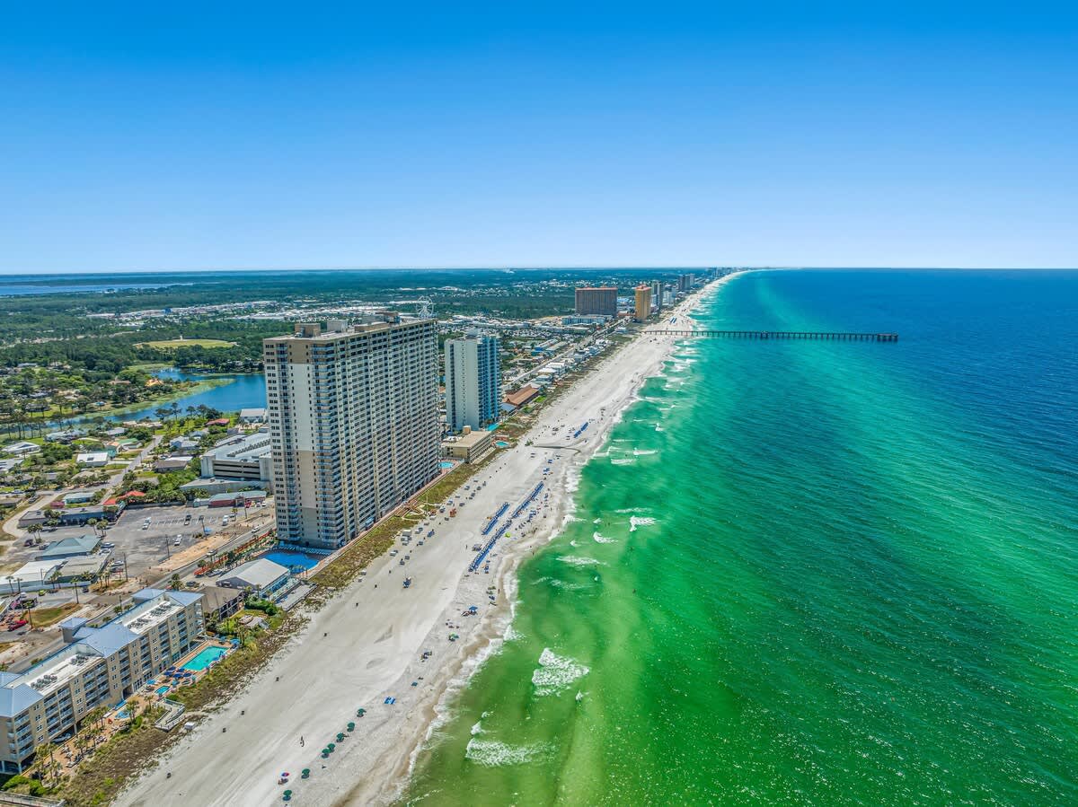 Tidewater 2615 – Aerial view of beachfront with high-rise buildings, sandy beach, and turquoise water.