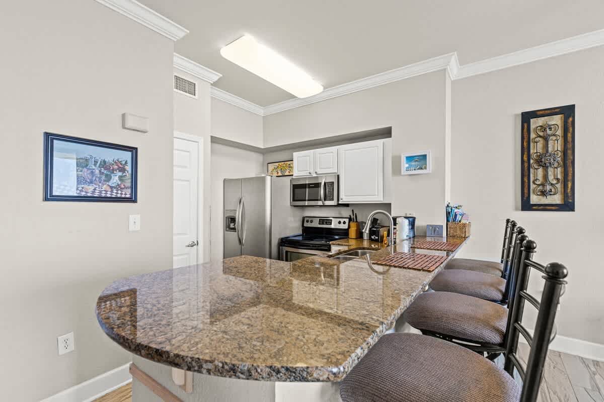 Tidewater 2615 – Modern kitchen with granite countertop, stainless steel appliances, and bar seating for four.