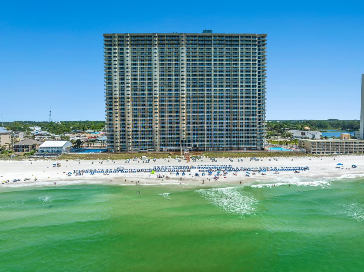 Tidewater 2615 – A tall beachfront building overlooking a sandy beach with sun loungers and clear green water.