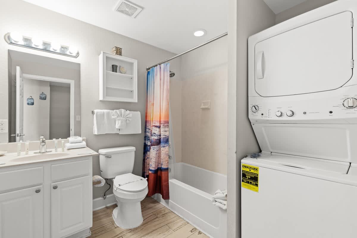 Tidewater 2615 – Bathroom with shower/tub combo, vanity, laundry unit, and ocean-themed shower curtain.